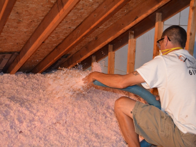 man putting down insulation in attic